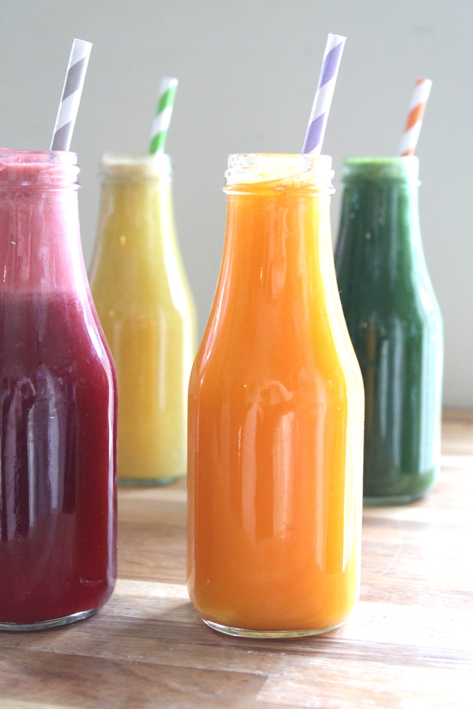 four bottles of juice with straws in them
