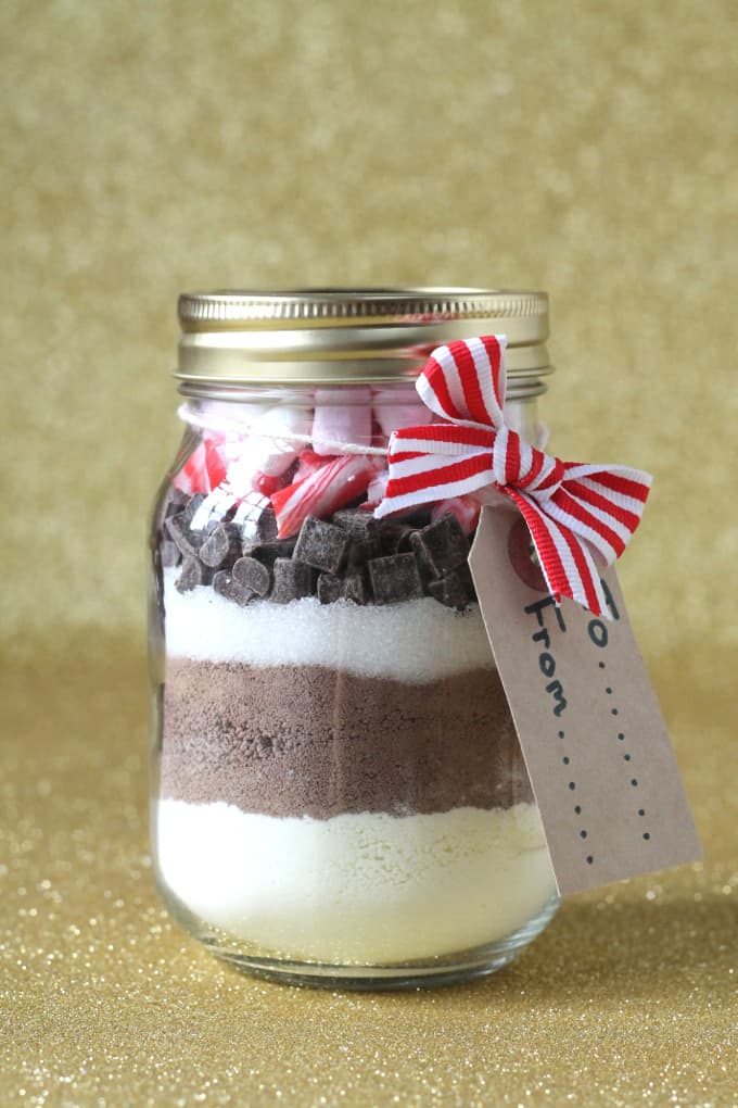 hot chocolate Christmas present in a glass jar with a red stripy ribbon and a cardboard gift tag.