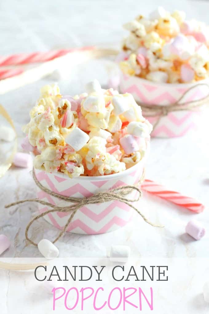 Candy Cane Popcorn in pink and white cardboard cups with red and white candy canes and mini marshamallows sprinkled around.