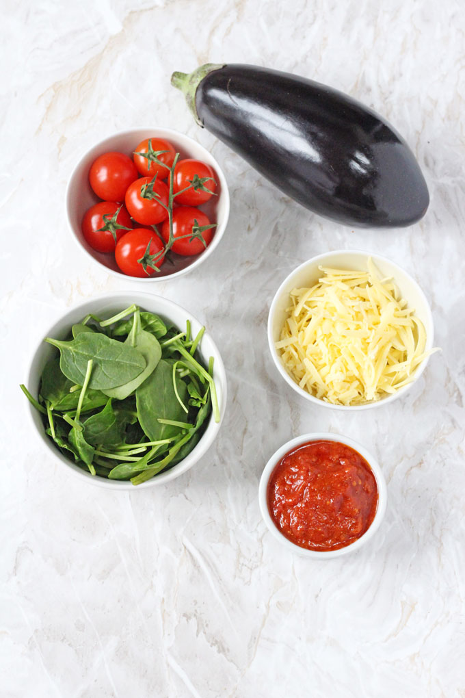mini aubergine pizza ingredients in white ramekin dishes on a white marble surface