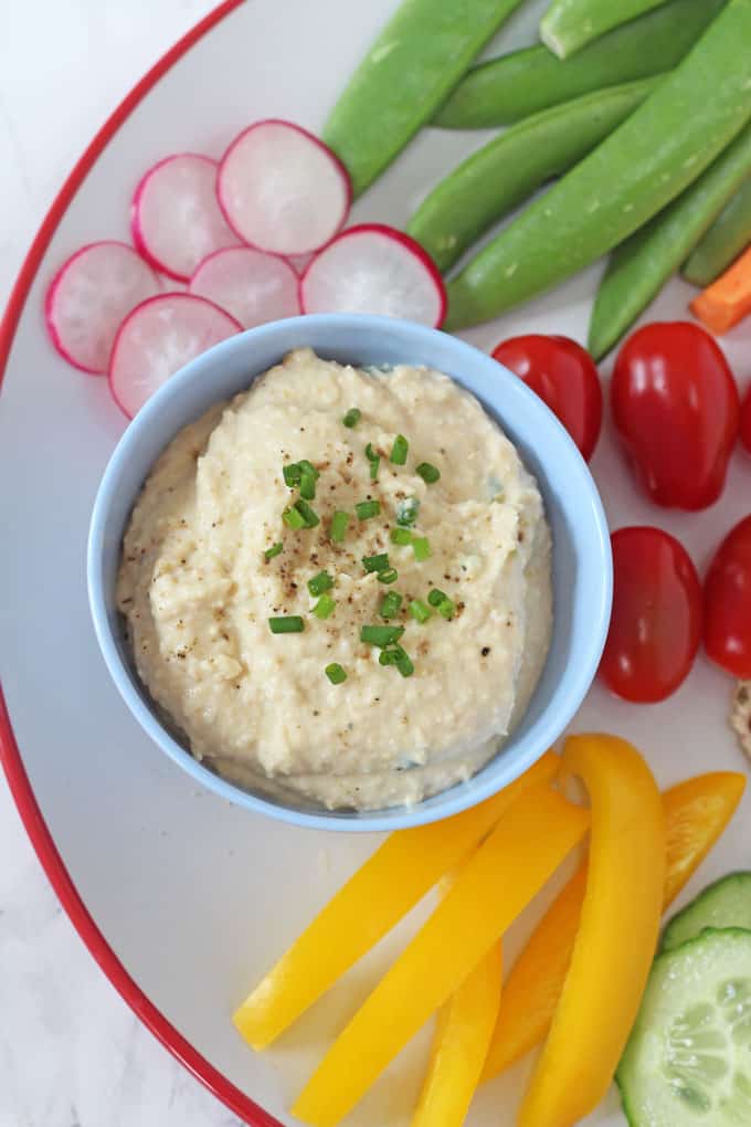 a close up of the chickpea dip in the blue ramekin topped with chopped chives.