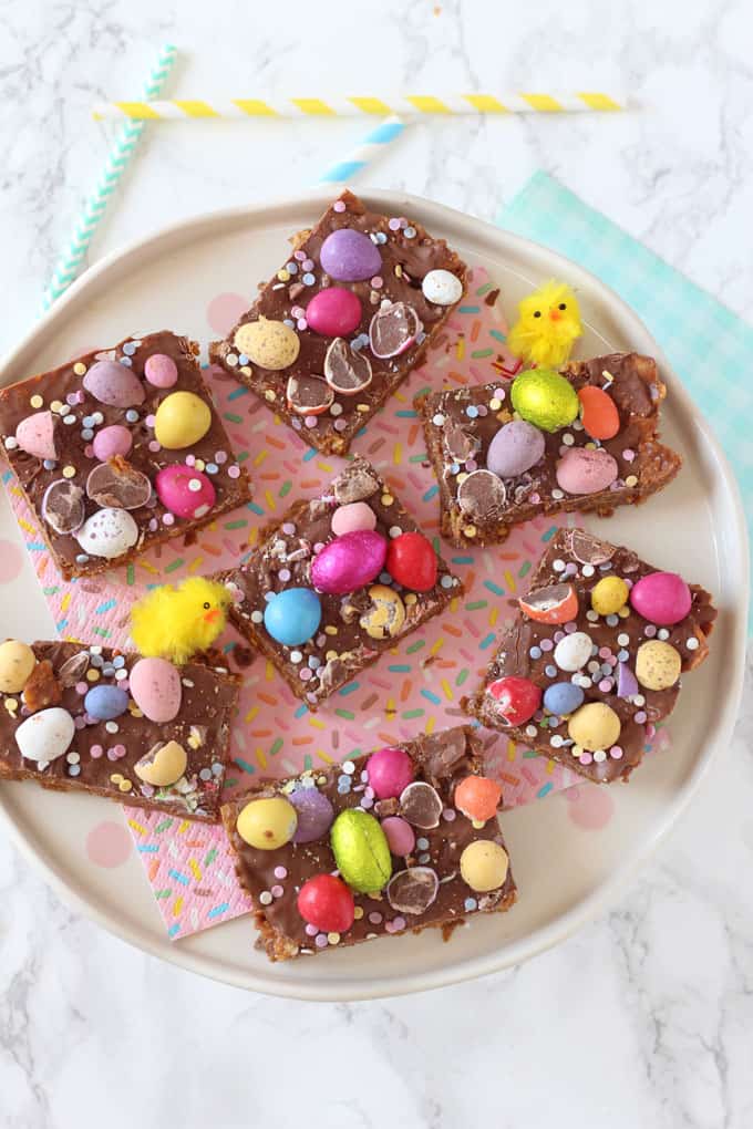 7 squares of Easter Cornflake Crunch served on a confetti themed napkin with mini easter chick decorations