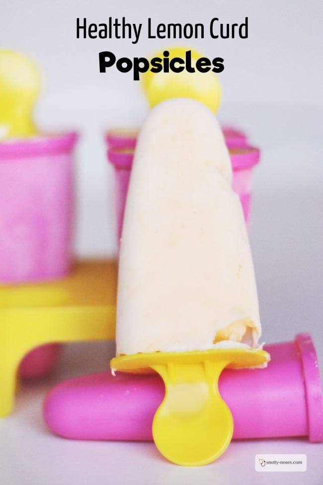 a lemon curd popsicle on a yellow popsicle stick with the pink popsicle holder in the background.