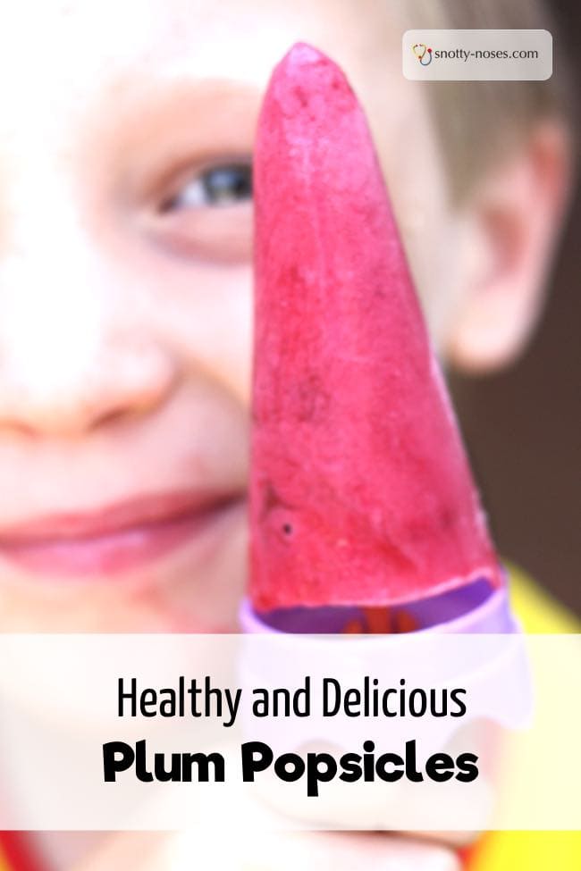 a male child holding up a plum popsicle.