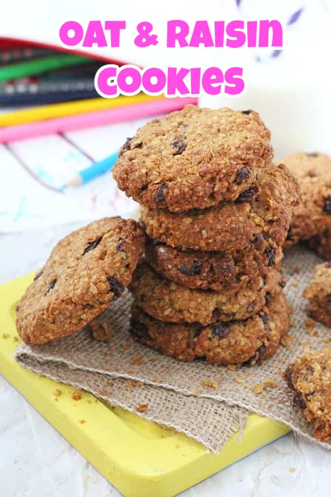 a stack of oat and raisin cookies on a hessian napkin on top of a yellow wooden chopping board.