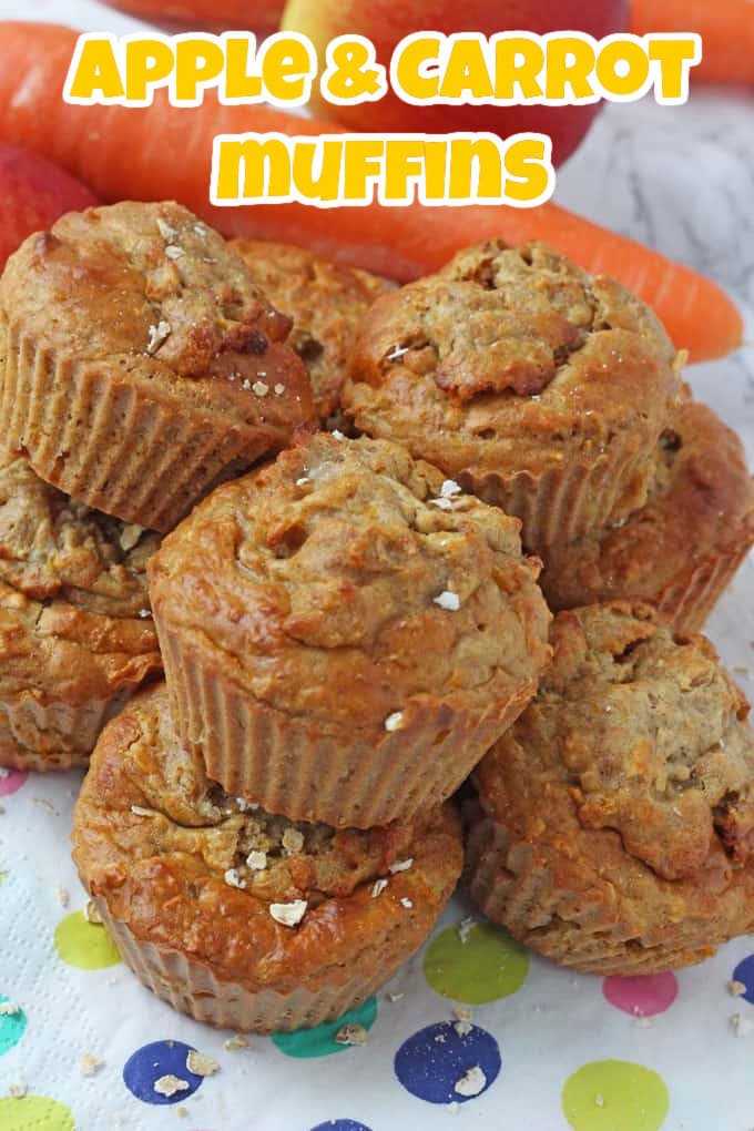 Apple & Carrot Muffins stacked in a pile on brightly coloured polka dot napkins with some carrots in the background.