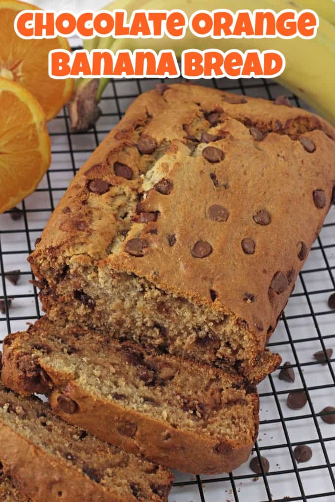 A loaf of chocolate orange banana bread that has been partially sliced on a wire cooling rack.