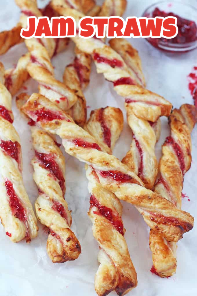 Jam straws on a grey and white marble background with a small ramekin of strawberry jam on the side.