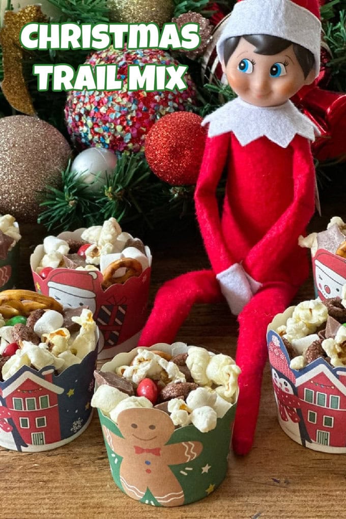 Elf on The Shelf figure surrounded by mini Christmas themed paper cups filled with Elf On The Shelf Trail Mix.