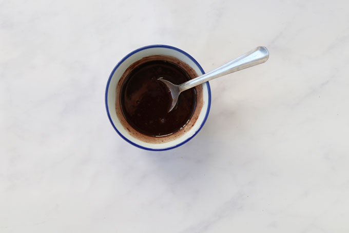 melted coconut oil in a cup with the honey, cocoa powder and vanilla extract.