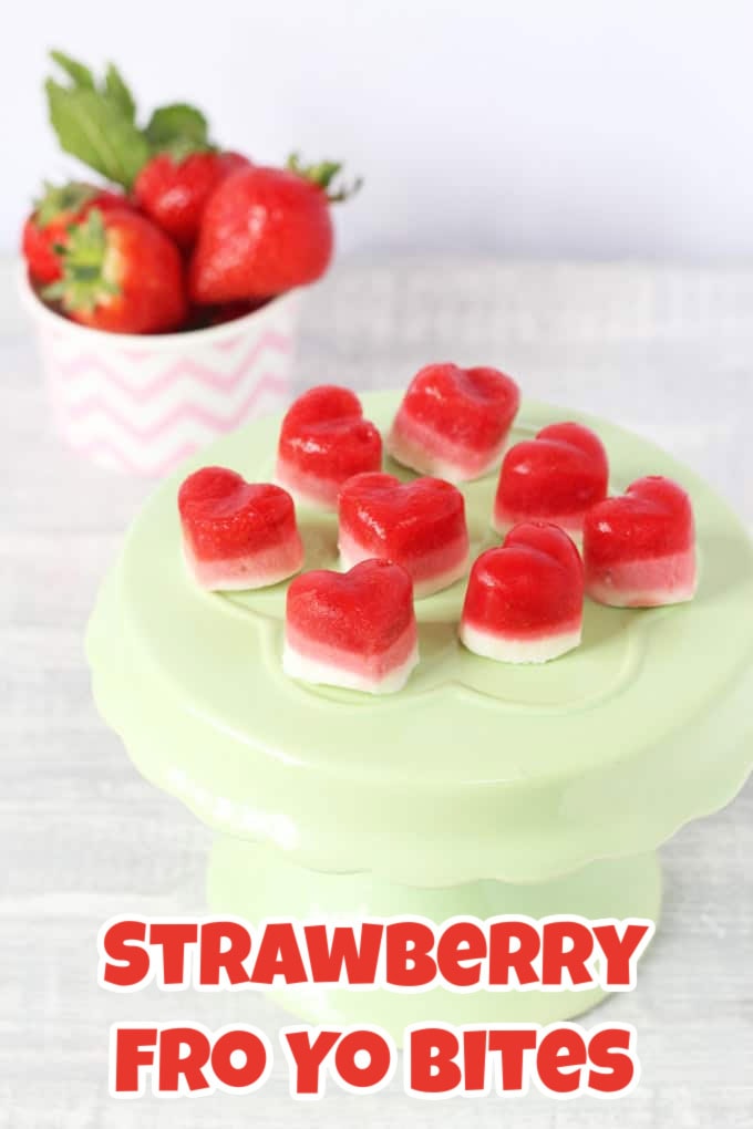 Red and white yoghurt bites in heart shapes arranged on a small light green cake stand.
