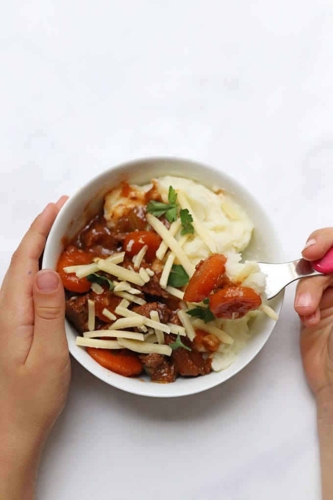 a kid friendly portion of beef casserole served with mashed potato and cheese