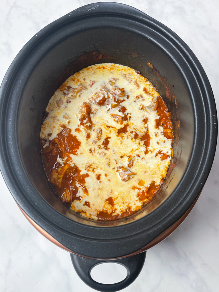 The cream ingredient now added to the slow cooker on top of the cooked ingredients.