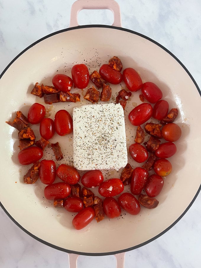 It's starts with oil, cherry tomatoes, chorizo and garlic in a large oven dish. Then adding a whole block of feta to the middle along with some seasoning.