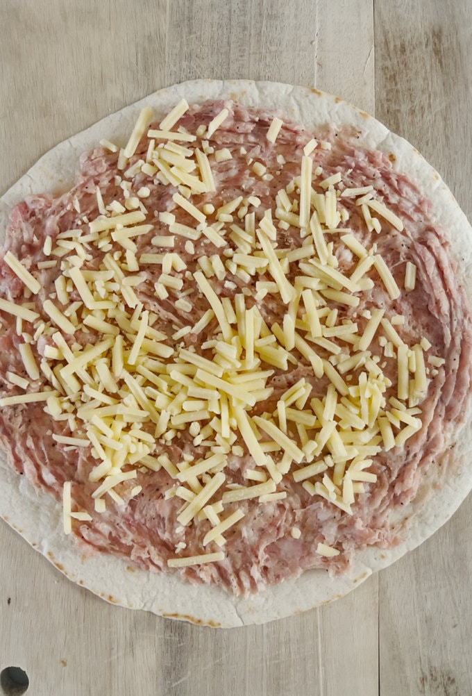 Grated cheese sprinkled onto sausage meat.