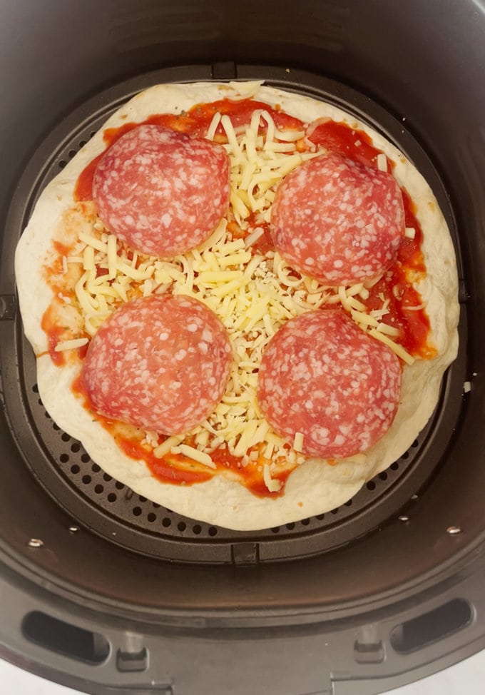 Tortilla in the air fryer with all the ingredients added on top.