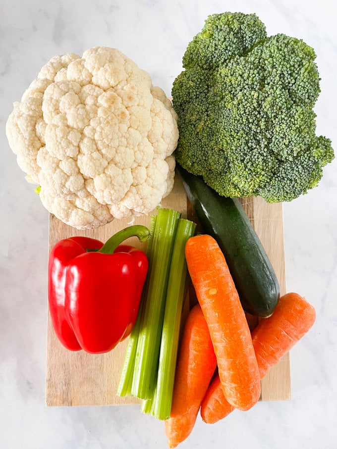 A selection of fresh vegetables presented on a wooden chopping board.