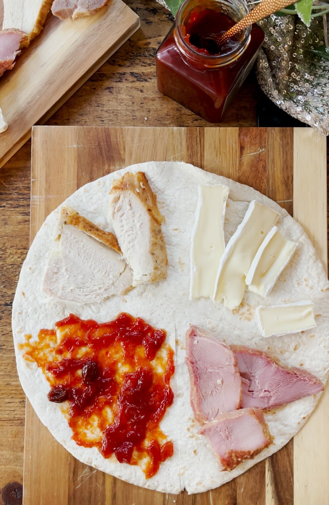 Open wrap laid on a wooden work surface, with each of the Christmas Leftovers Toasted Wrap ingredients added to a quarter