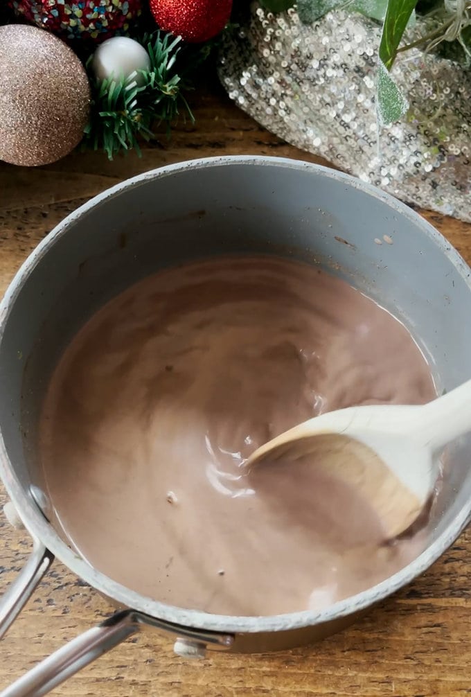 Ingredients being stirred in a saucepan with a wooden spoon.