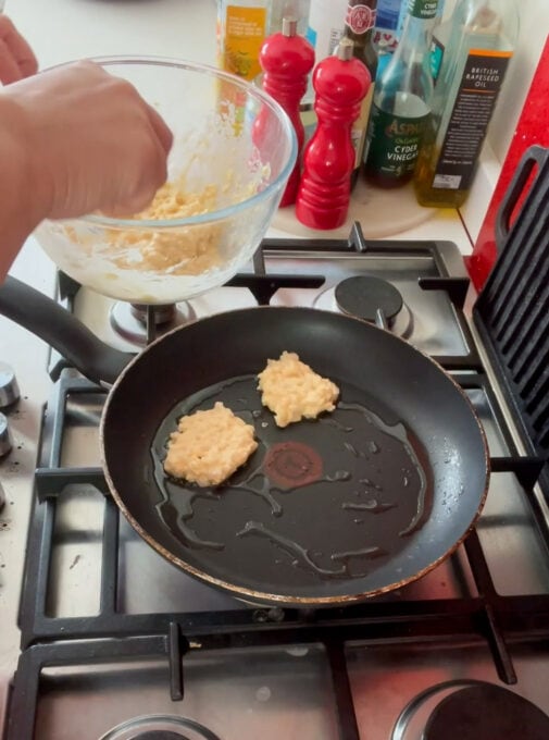 Fritters being added to a frying pan ready to be cooked.