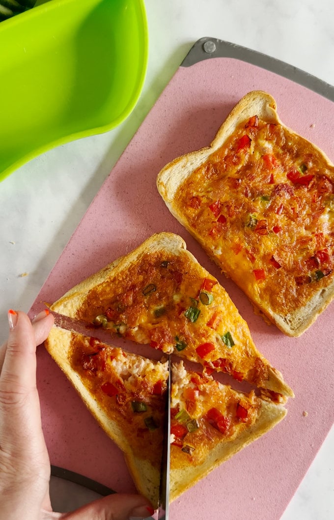 Cooked Omelette toast being cut into triangle shaped pieces.