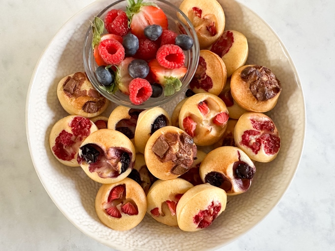 Easy Make-Ahead Breakfast Recipes & Ideas For Kids - Mini Pancake Bites served in a white bowl with a ramekin of chopped fresh berries