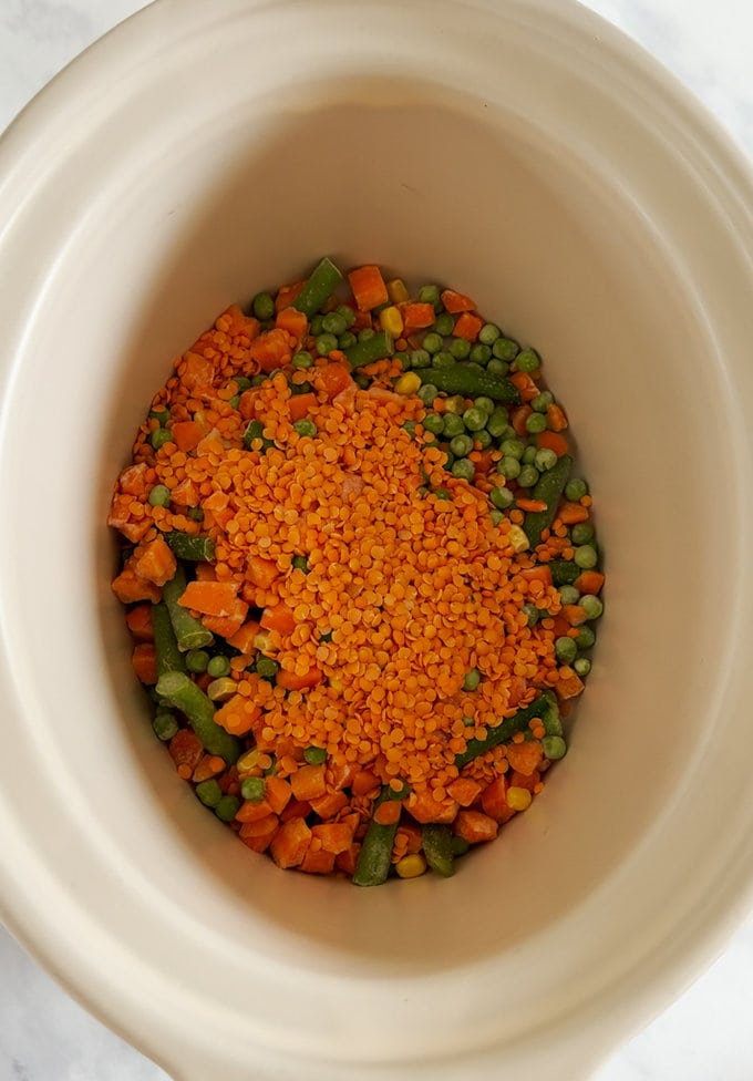 Raw ingredients added to the slow cooker bowl in preparation for cooking.