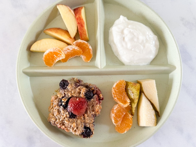 Easy Make-Ahead Breakfast Recipes & Ideas For Kids - Baked Berry Oats Bar served on a kids divided plate with chopped apple, satsuma and greek yogurt.
