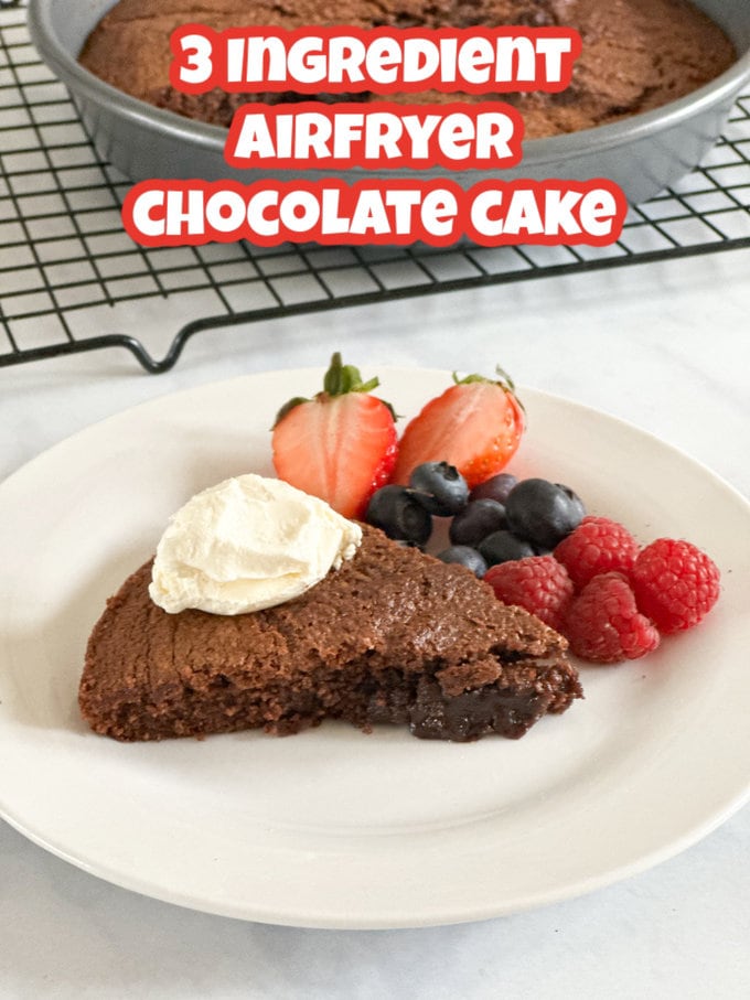 A slice of Airfryer Chocolate Cake on a small white side plate, topped with a dollop of greek yogurt on top and some fresh strawberries, blueberries and raspberries on the side of the plate.