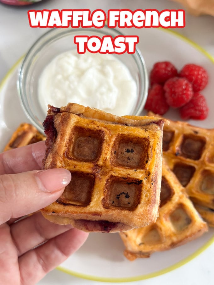 Small squares of waffle french toast served with a small glass ramekin of yogurt and fresh raspberries.