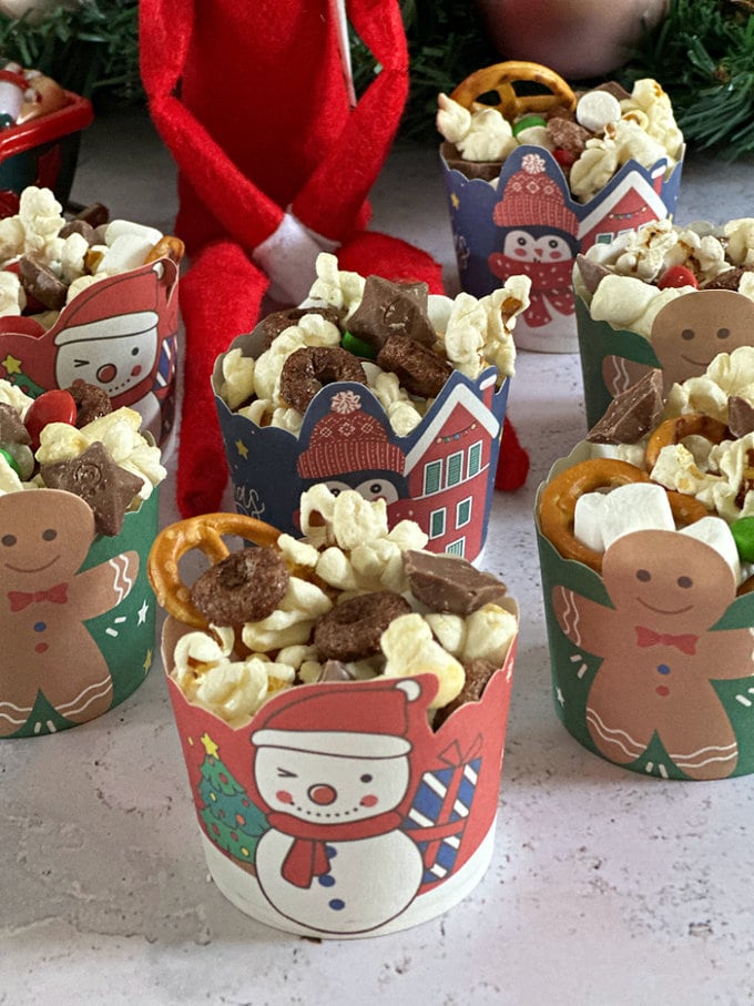 Bright and colorful card muffin case with snowman and gingerbread men on them full of trail mix.