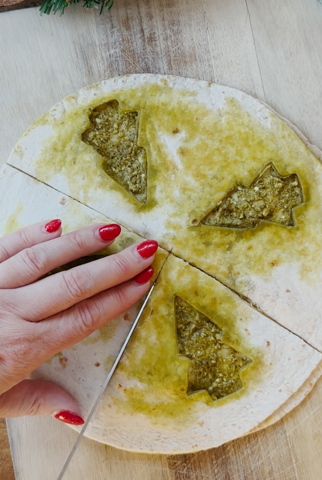 Cooked tortilla being sliced into triangle sections ready to be eaten.