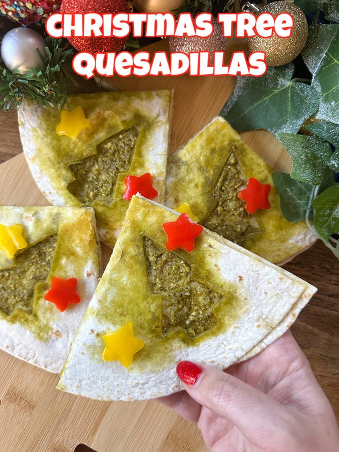Christmas Tree Quesadillas on a wooden chopping board with Christmas decorations in the background.