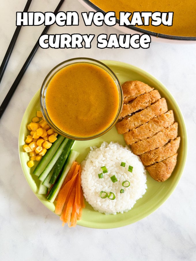 Hidden veg katsu curry sauce served in s small glass bowl, accompanied by sliced,battered chicken, white rice and chopped veggies.