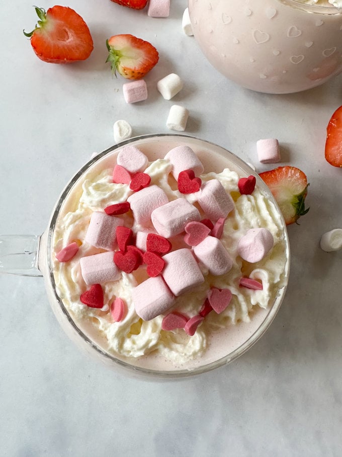 served in a pretty glass mug and garnished with squirty cream,mini marshmallows and heart shaped sprinkles.