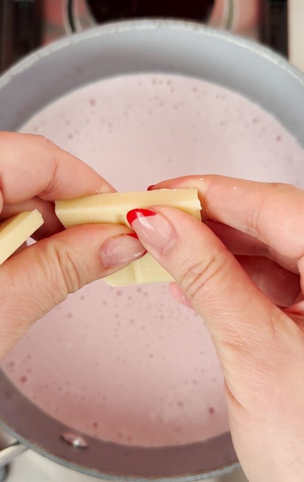 White chocolate being broken into pieces and added to the milk.