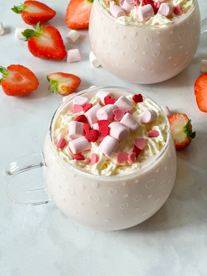 served in a pretty glass mug and garnished with squirty cream,mini marshmallows and heart shaped sprinkles.