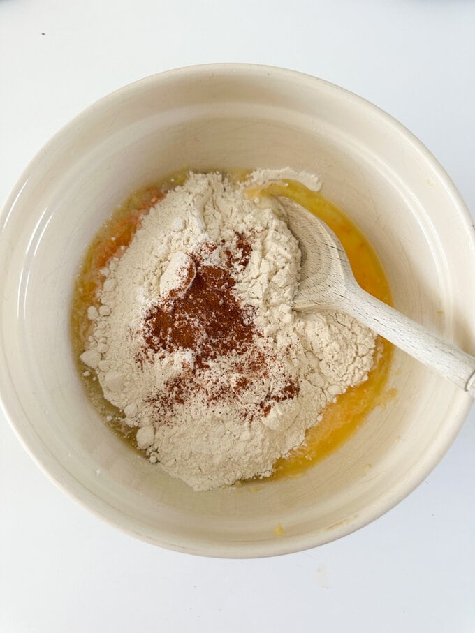 Ingredients for Mini Carrot Banana Bread being mixed up in a large bowl with a wooden spoon.