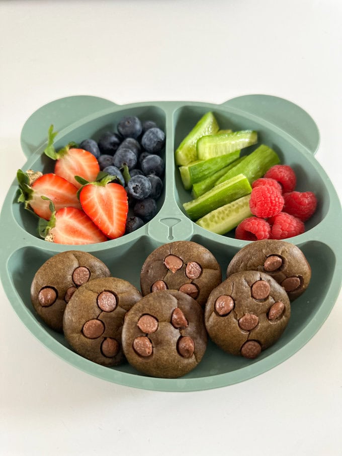 Mini Chocolate Spinach Muffins served on a divided child's plate with fresh berries and cucumber batons.