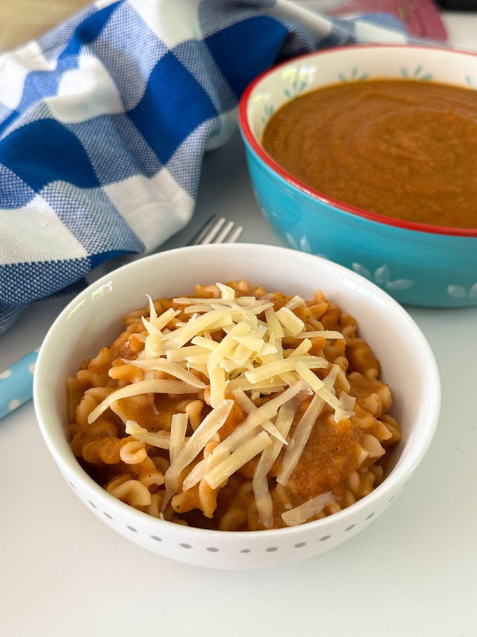 No tomato sauce mixed with cooked pasta and garnished with grated cheddar cheese.