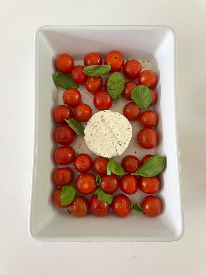 Ingredients being added into a white rectangle shaped oven proof dish.