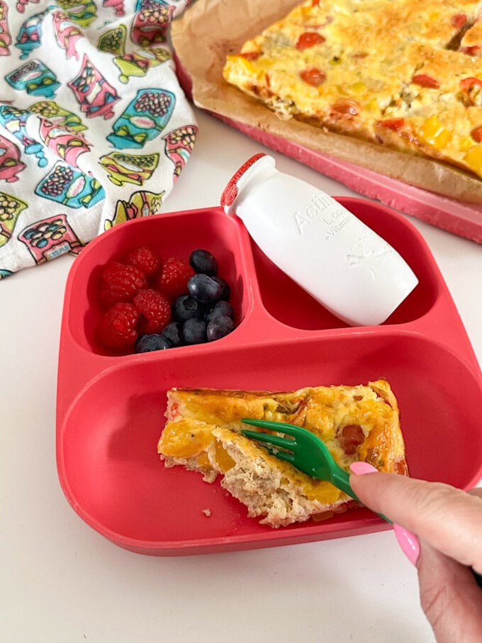 Sliced frittata being eaten with a green fork.