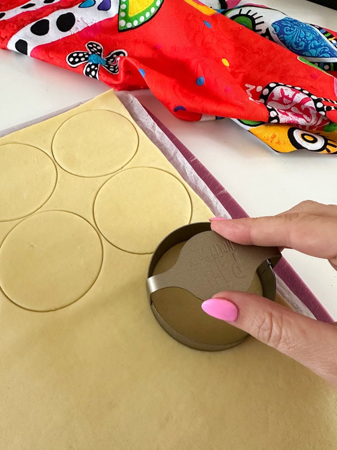 Cutting out 12 circles in the rolled pastry with a pastry cutter.