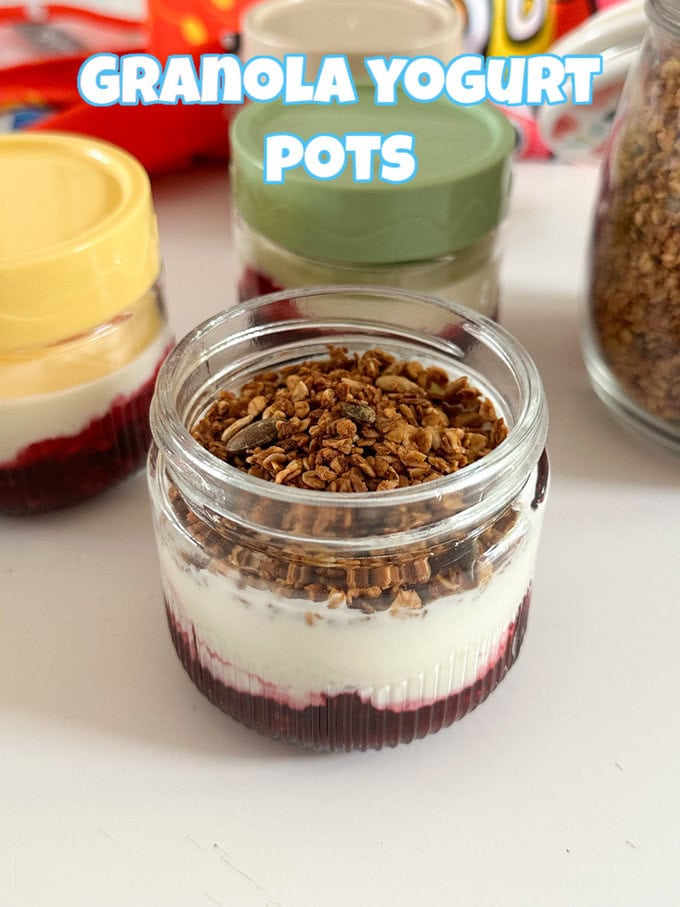 3 small glass pots containing jam, yogurt and granola with brightly coloured lids.