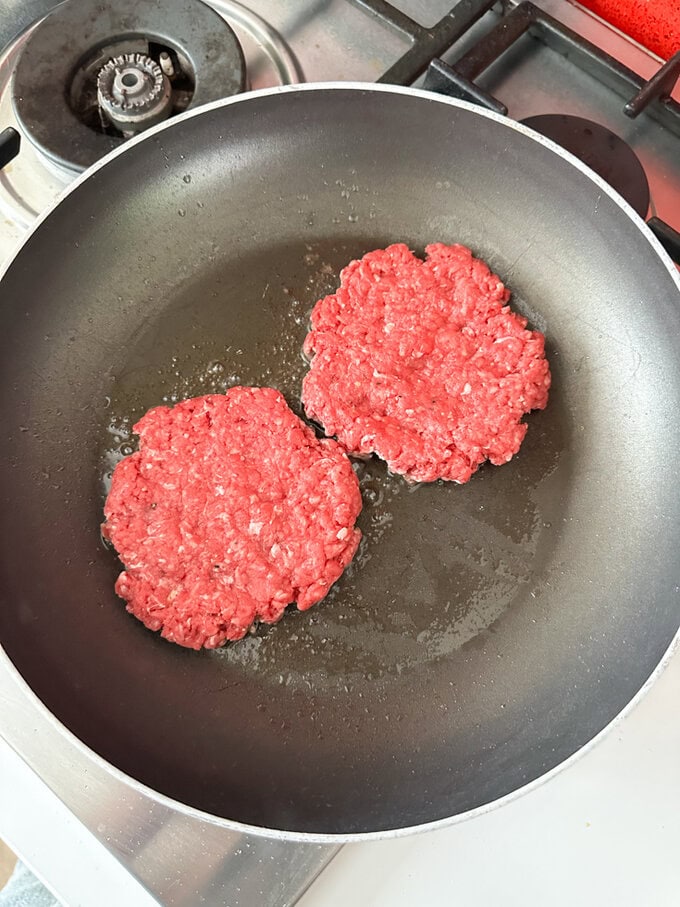 Burgers frying in a pan.