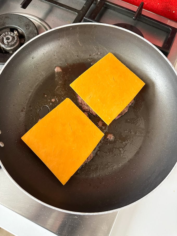Cheese squares added to the frying burgers.