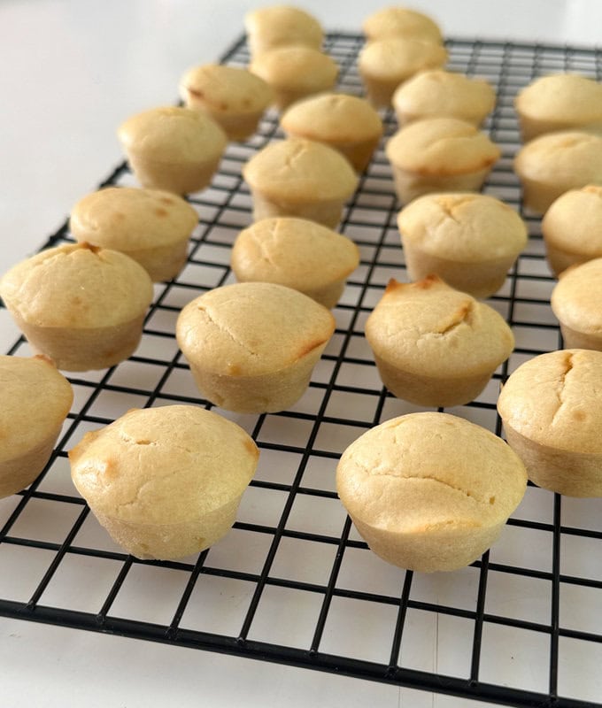 Mini lemon muffins fresh out of the oven and left to cool on a wire rack tray.