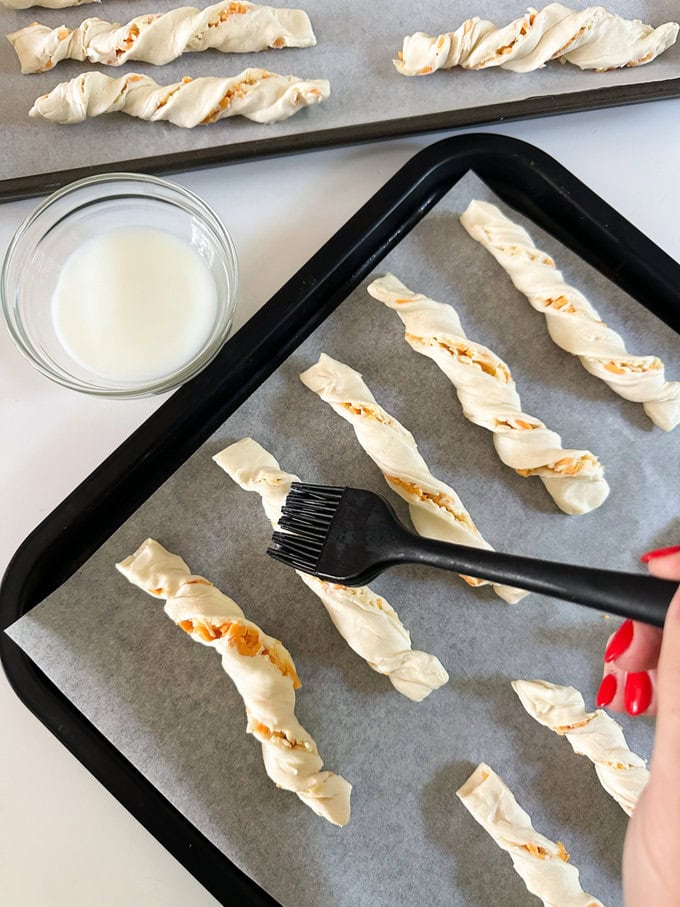 Brushing cheese twists with milk.