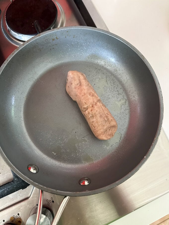Skinned sausage laying in a frying pan.