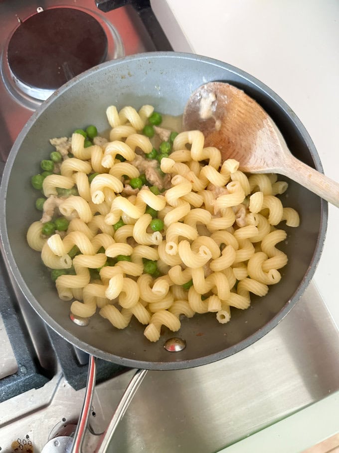 All ingredients being mixed together in a pan using a wooden spoon.